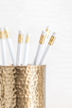 White pencils in a gold hammered pen cup